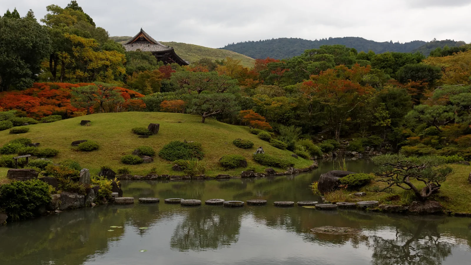 Isuien Garden in Nara with a pond, trees and distant temple roofs