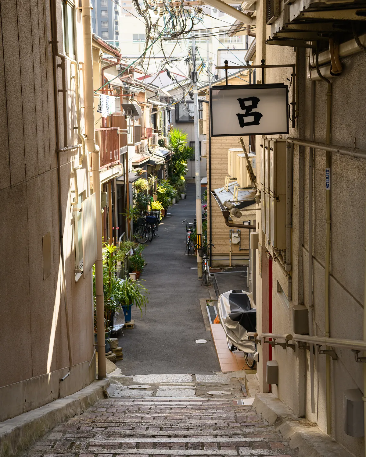 Narrow residential alley in Karahori, Osaka with old buildings, plants and bicycles
