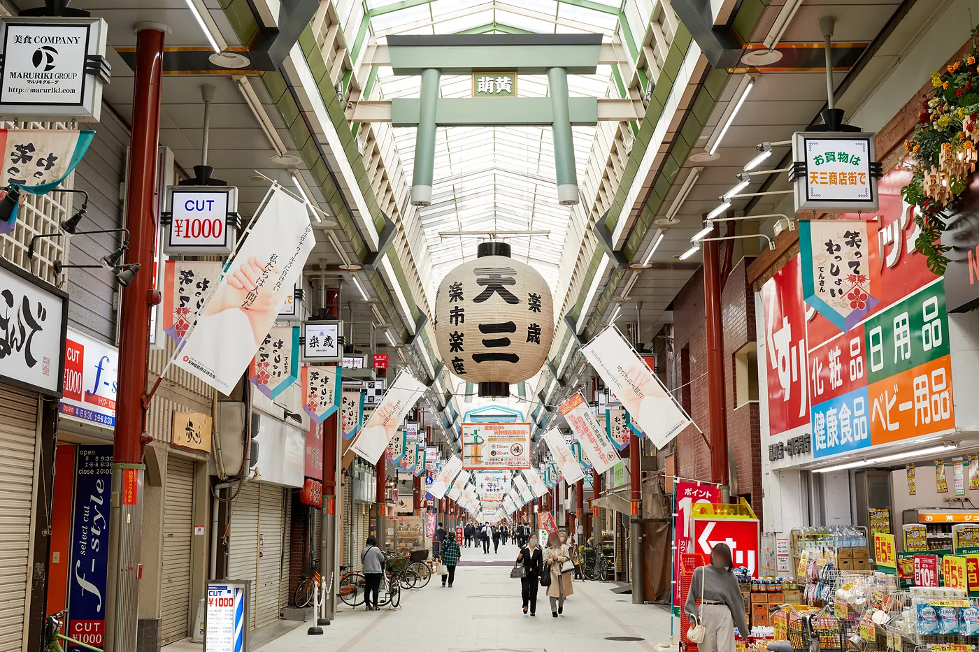 Covered Tenjinbashisuji Shopping Street in Osaka with shops, banners and a large lantern
