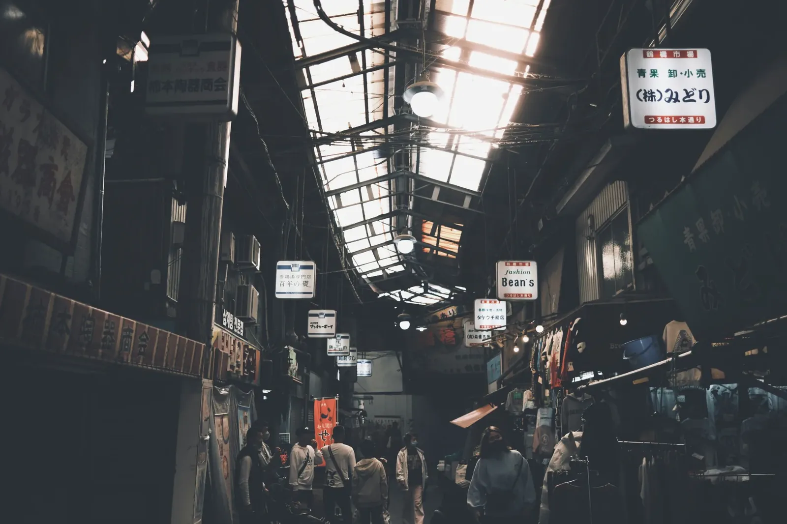 People walking through a narrow covered alley in Tsuruhashi Market