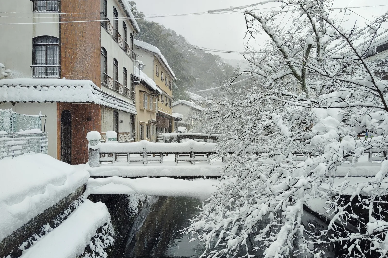 Snow-covered Otani River and traditional buildings in Kinosaki Onsen