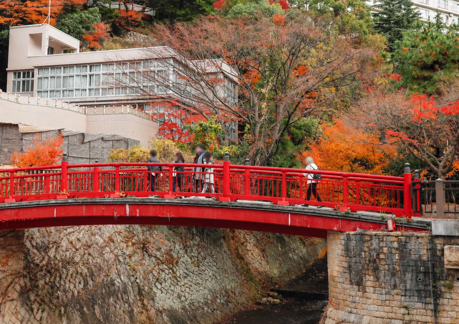 Red Nene Bridge surrounded by autumn leaves in Arima Onsen