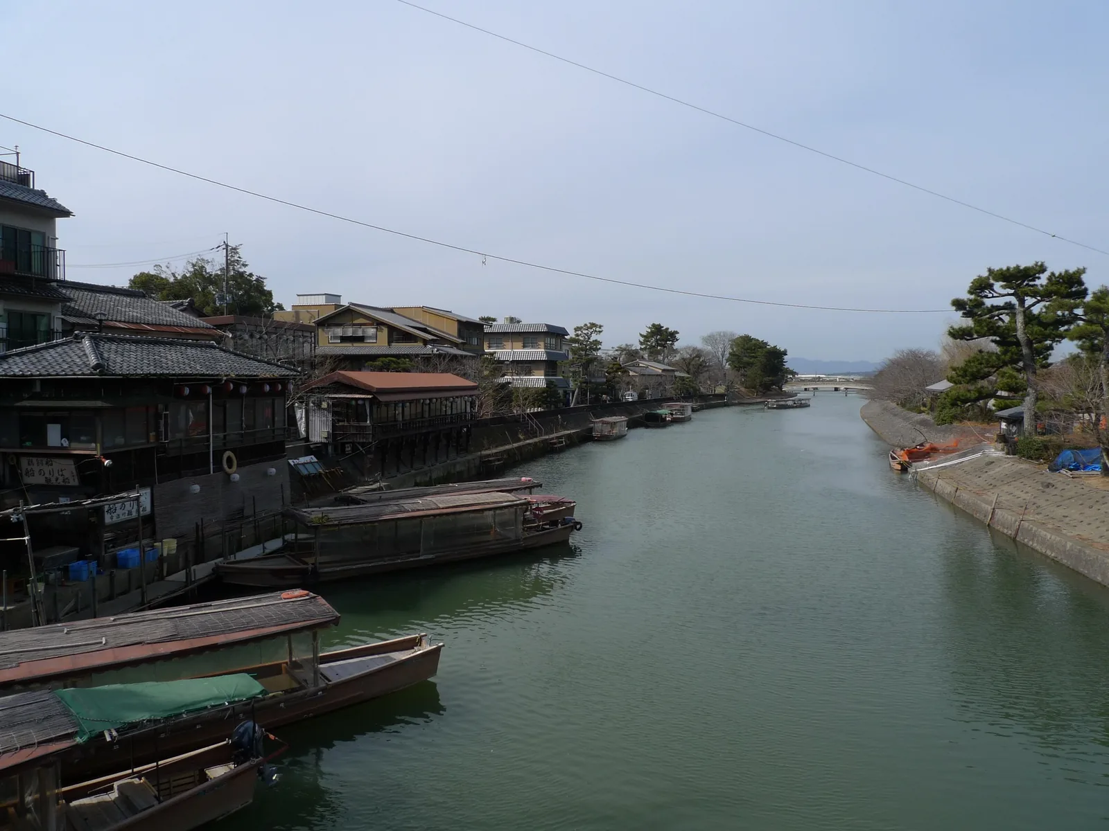 Uji River with traditional sightseeing boats and forested hills